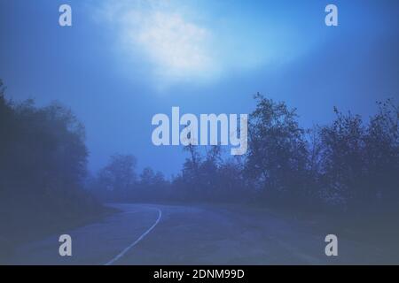 Car driving on mountain foggy road at night Stock Photo