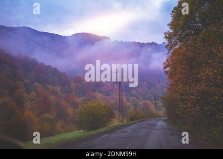 Car driving on mountain foggy road in early foggy morning Stock Photo