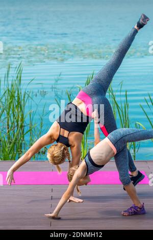 Woman and child doing handstand exercise on the grass near the lake. Yoga nature concept Stock Photo