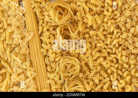 Italian foods concept and menu design. Various kind of Pasta Farfalle, Pasta A Riso, Orecchiette Pugliesi, Gnocco Sardo and Farfalle on white stone background with flat lay. Background Stock Photo