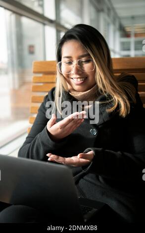 Woman at train station using laptop Stock Photo