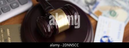 Wooden gavel for judge lies on table next to one hundred dollar bills and bank credit cards. Stock Photo