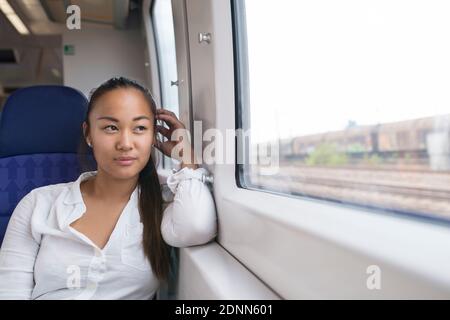 Woman in train looking through window Stock Photo