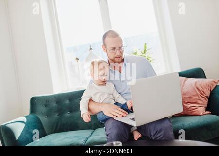 Father and toddler son using laptop Stock Photo