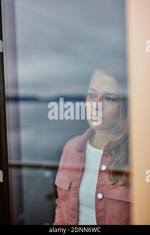 Woman looking through window Stock Photo