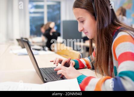 Girl in classroom using laptop Stock Photo