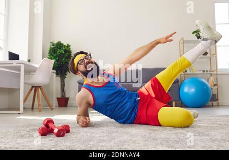Happy positive funny man working out at home, doing side lying leg lifts and laughing Stock Photo
