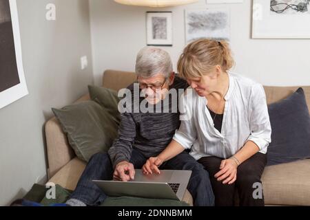 Couple using laptop on sofa Stock Photo