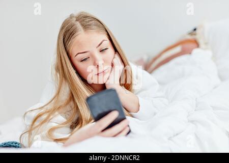 Woman in bed using cell phone Stock Photo
