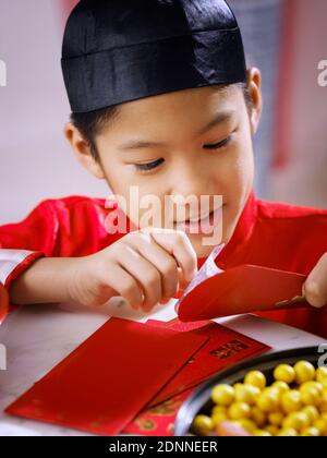 Close-up Of Boy Holding Envelope With Paper Currency At Table