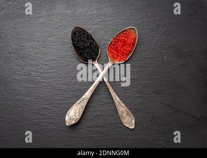 grainy caviar of paddlefish fish and red chum salmon caviar in a spoon, black background, top view Stock Photo