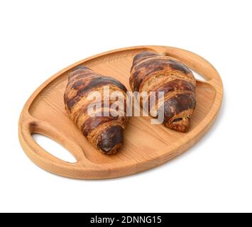 two baked croissants lie on a wooden tray, food isolated on white background Stock Photo