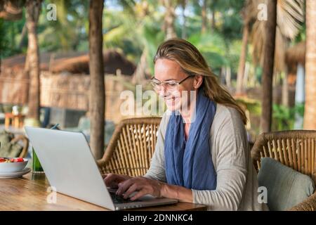 Woman in outdoor cafe using laptop Stock Photo