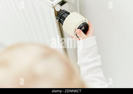 Hand adjusting thermostat valve on radiator Stock Photo