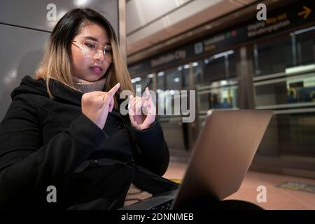 Woman at train station using laptop Stock Photo