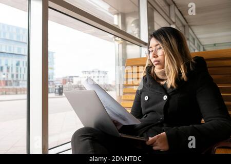 Woman at train station using laptop Stock Photo