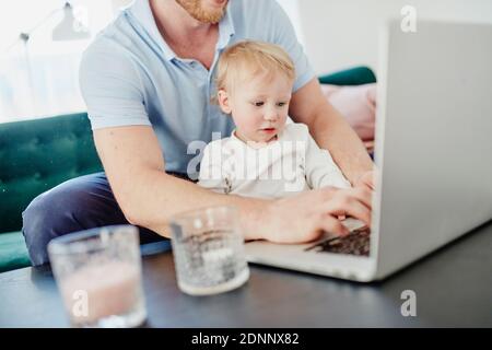Father and toddler son using laptop Stock Photo