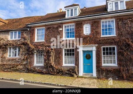 Georgian style terraced cottage (Church Hill House) in Church Hill, Midhurst, West Sussex, in winter with a Christmas wreath on its blue front door Stock Photo