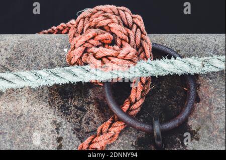 Sailor knots on jetty tied in round metal ring Stock Photo