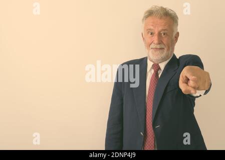 Studio shot of handsome senior bearded businessman pointing at camera against white background Stock Photo