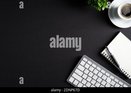 Black office desk table with cup of coffee, computer keyboard, notepad and pen. Flat lay, top view, copy space. Luxury, minimalist style workspace. Bu Stock Photo