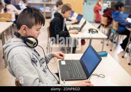 Boy in classroom using laptop Stock Photo
