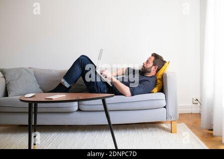 Man on sofa using laptop Stock Photo