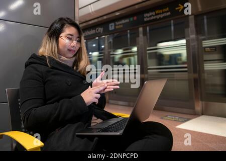 Woman at train station using laptop Stock Photo