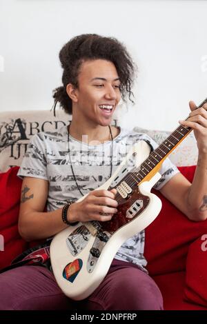 Young man playing guitar on sofa Stock Photo