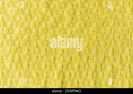 Cropped close up shot of yellow woolen knitting pattern of fall / winter season warm sweater, clearly visible fiber texture of stylish hipster knitwea Stock Photo