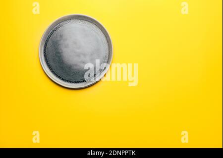 Gray empty ceramic plate on yellow Stock Photo