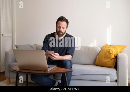 Man on sofa using cell phone Stock Photo