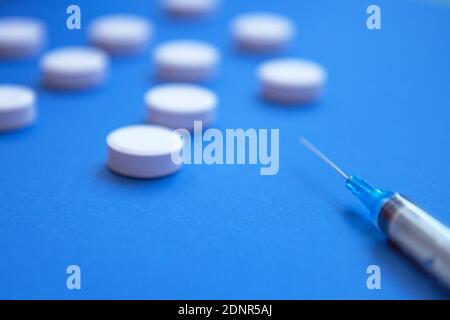 Set of white pills and syringe on blue background. Pills background. White tablets on a blue background Stock Photo