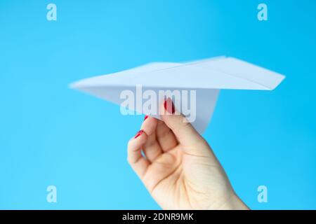 Female hand holding paper plane on blue background Stock Photo