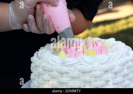 Person decorating a cake with a cream in a pastry shop Stock Photo