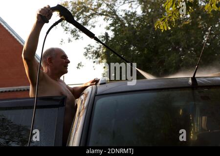 Senior man washing car with high pressure washer Stock Photo