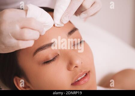 Cropped shot of a cosmetologist cleaning pores of a female client. Asian young woman having her skin cleansed by beautician Stock Photo