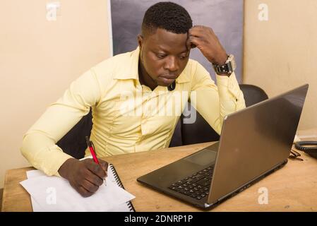 Close-up portrait of handsome confident businessman sitting at the table and carefully writes notes on paper inside the office Stock Photo