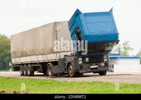Faulty truck on the side of the road. An old cargo tractor with a raised cab stands on the side of the road. Troubleshooting a technical malfunction Stock Photo