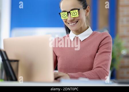 Stickers gluing to womans glasses. Eyes are drawing on piece of paper Stock Photo