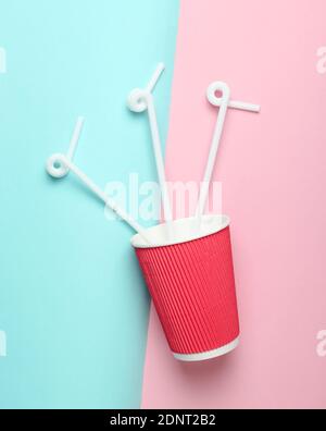 Paper coffee cup with cocktail straws on a colored pastel background, top view, minimalism. Stock Photo