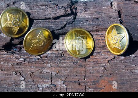 Buttons with the symbols of the USSR. Four yellow button of a military clothes of the USSR period with a star, a sickle and a hammer on old wooden bar Stock Photo