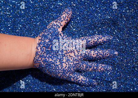 Child's hand in blue rhinestones. A lot of blue glue rhinestones and the kids hand Stock Photo