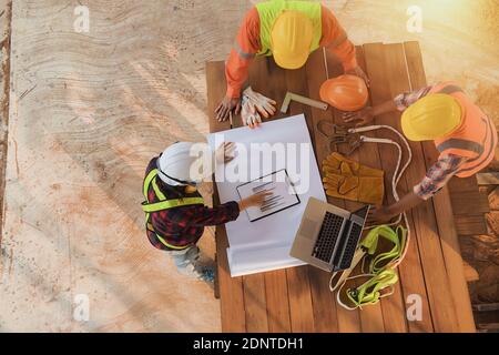 Overhead view of a three construction workers looking at graphs, Thailand Stock Photo