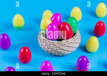 Colorful Plastic Easter Eggs in a wicker basket on blue background Stock Photo