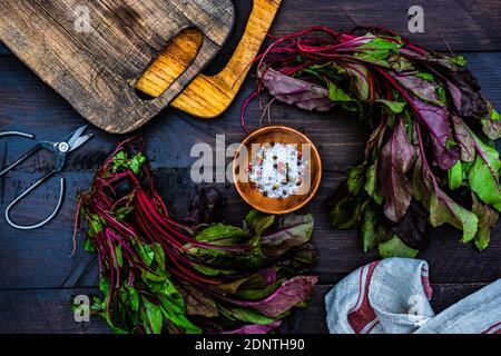 Beetroot leaves with sea salt and peppercorns on a chopping board Stock Photo