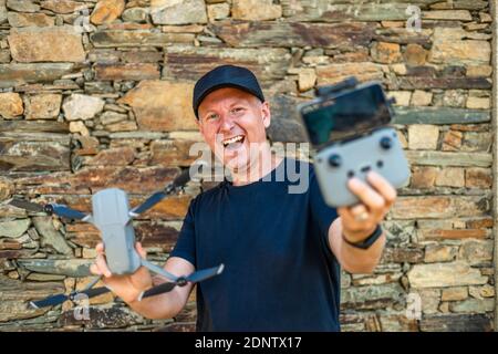 Excited man holding his new drone with remote and phone ready to fly Stock Photo