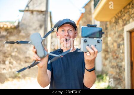 Excited man holding his new drone with remote and phone ready to fly Stock Photo