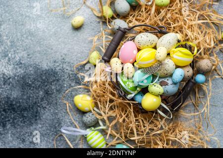 Multi coloured Easter eggs in a basket surrounded with straw Stock Photo