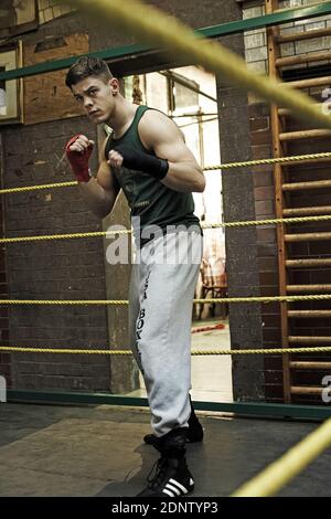 Young athletic man preparing for boxing competitions, training defense and attacks in boxing club. Stock Photo